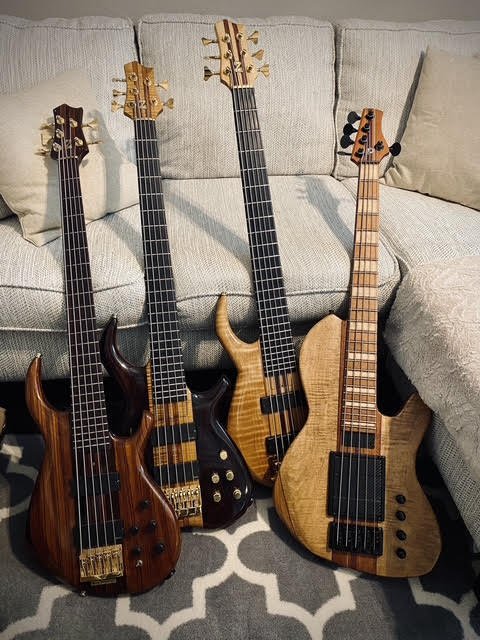 Four custom basses lined against a couch